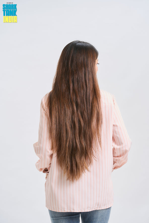 Person with long hair wearing a light pink shirt on a white background