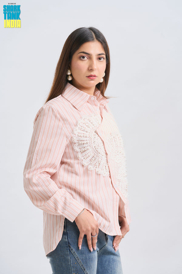 Woman wearing a light pink striped shirt with lace details on a white background