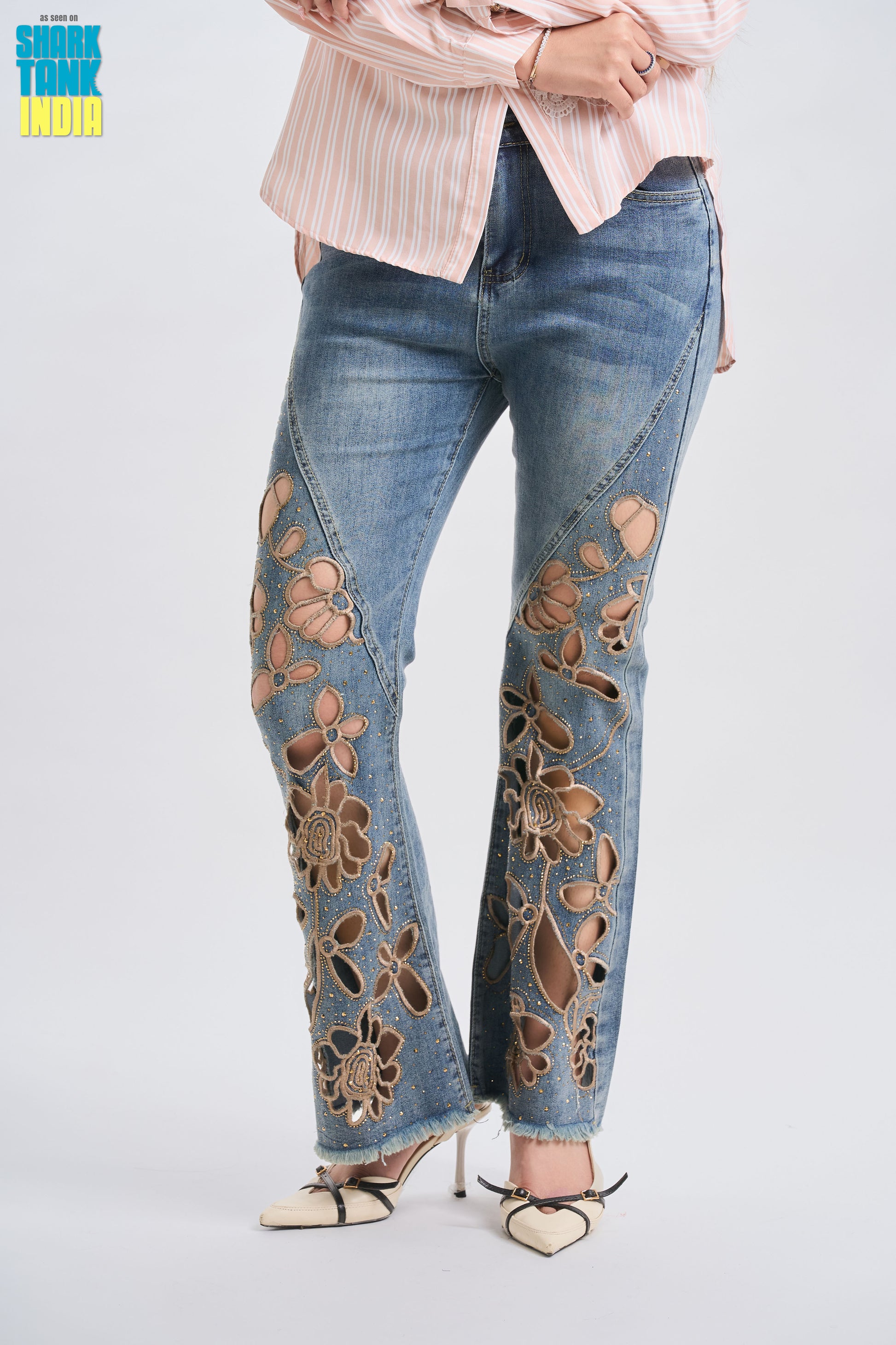 Flared jeans with floral embroidery worn by a person on a light gray background