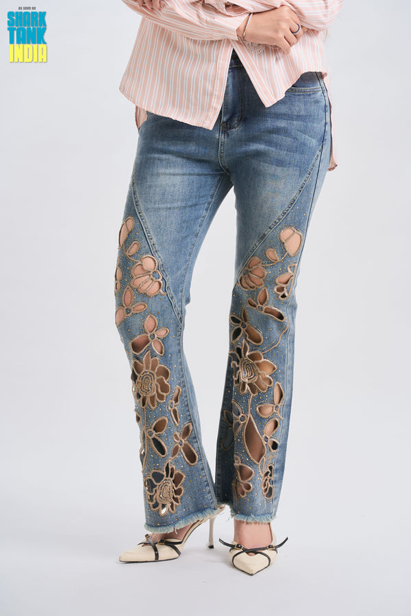 Flared jeans with floral embroidery worn by a person on a light gray background