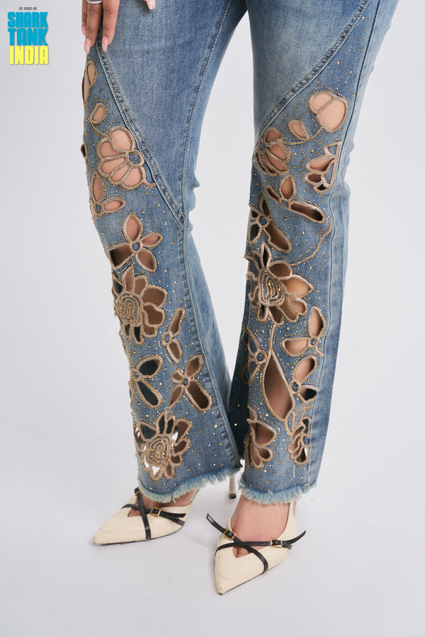 Denim jeans with floral cut-out design on a white background