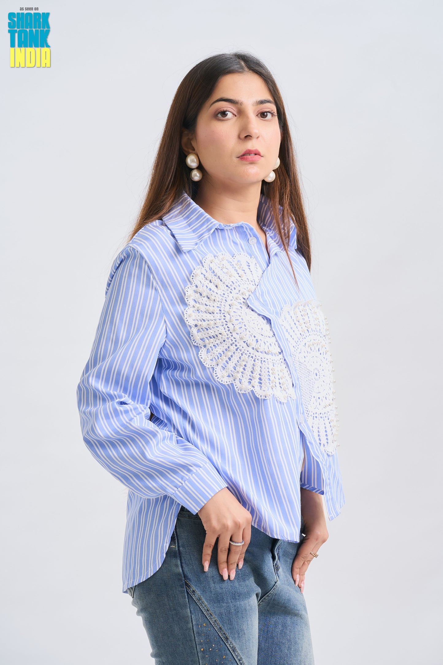 Woman wearing a blue striped shirt with a decorative white patch on a light gray background