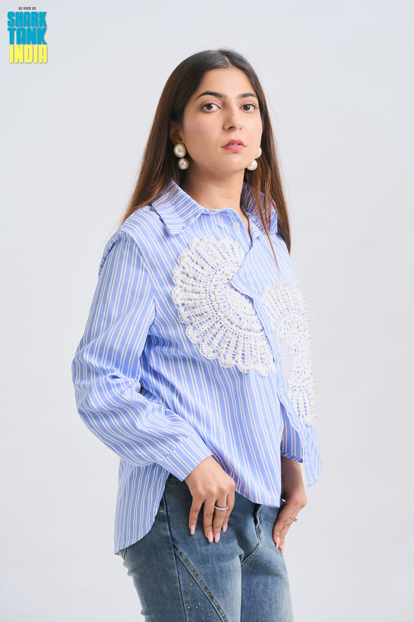 Woman wearing a blue striped shirt with a decorative white patch on a light gray background