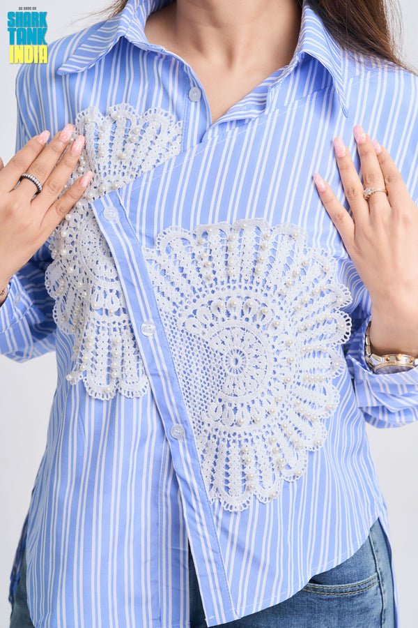 Blue striped shirt with decorative white patterns on a plain background