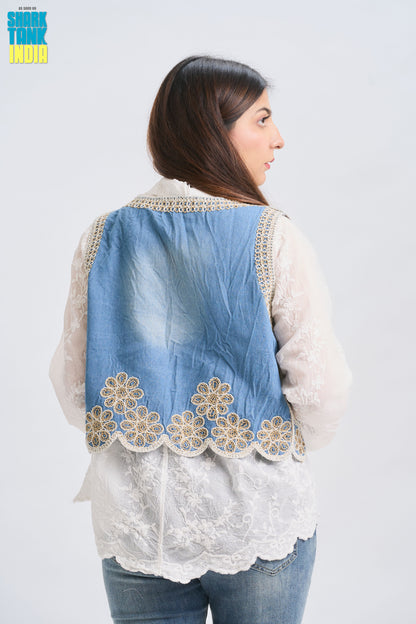 Woman wearing a denim vest with floral embroidery on a white background