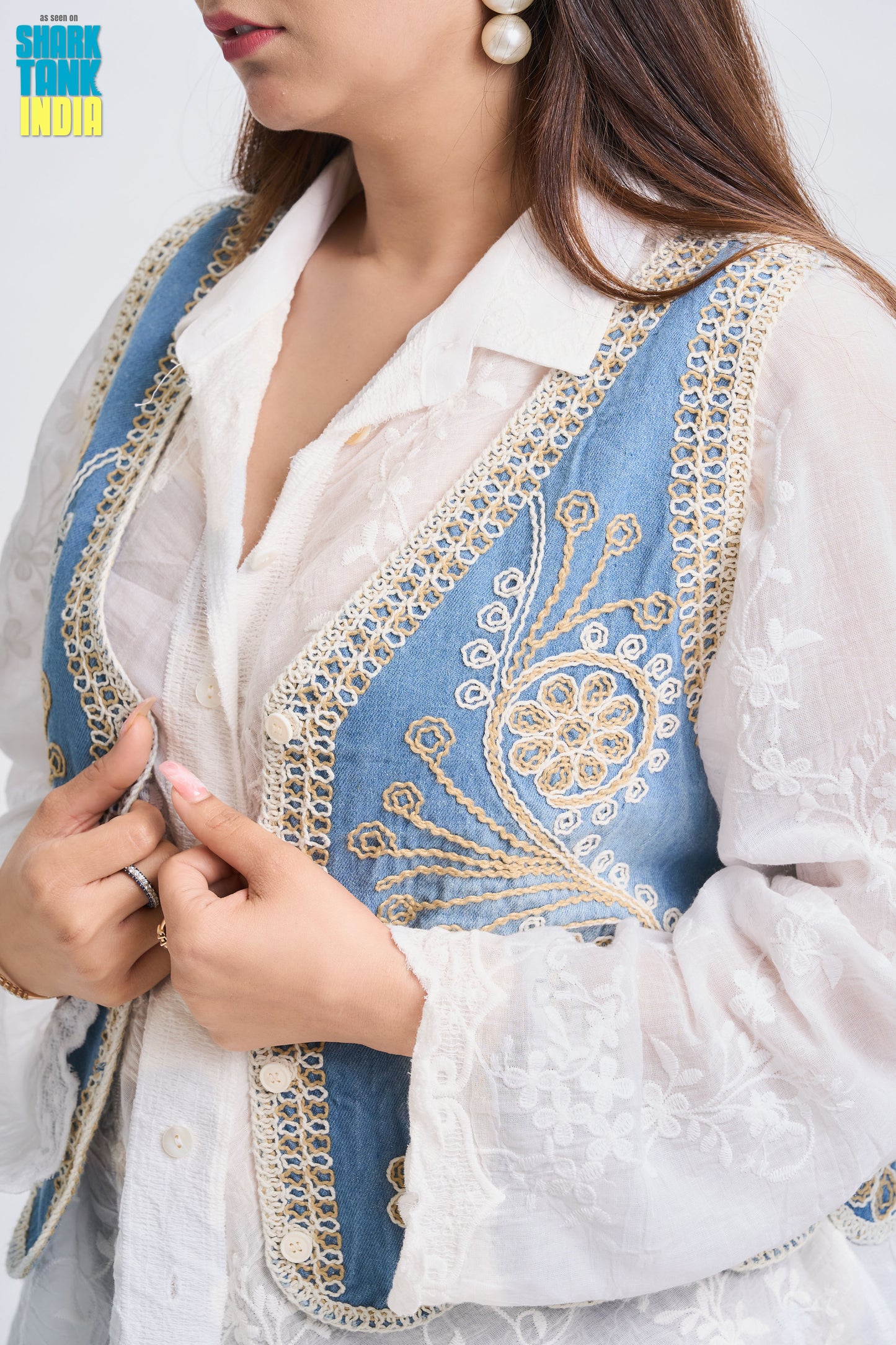Close-up of a person wearing a white and blue embroidered traditional outfit.