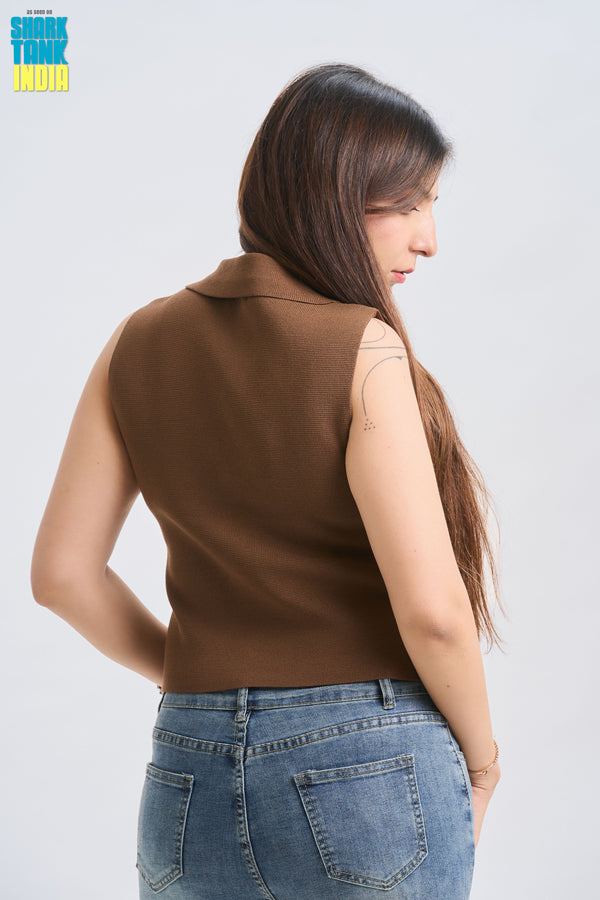 Woman wearing a brown sleeveless top and blue jeans on a white background