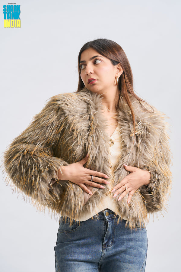 Woman wearing a fur jacket and jeans on a plain background