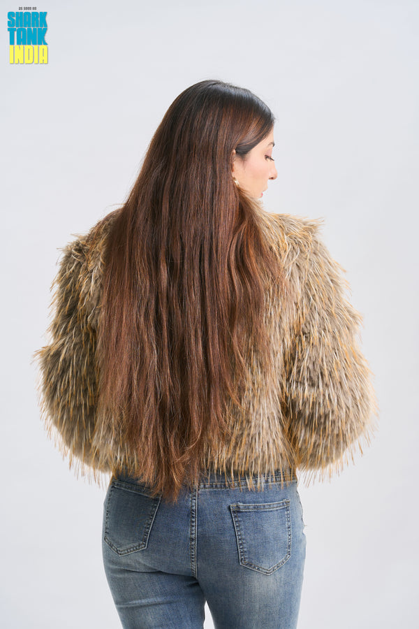 Person with long, wavy hair wearing a fur coat and jeans on a white background