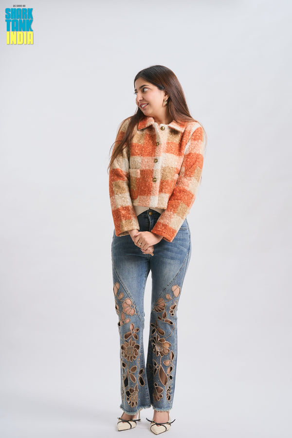 Woman wearing a plaid jacket and jeans with floral designs on a white background