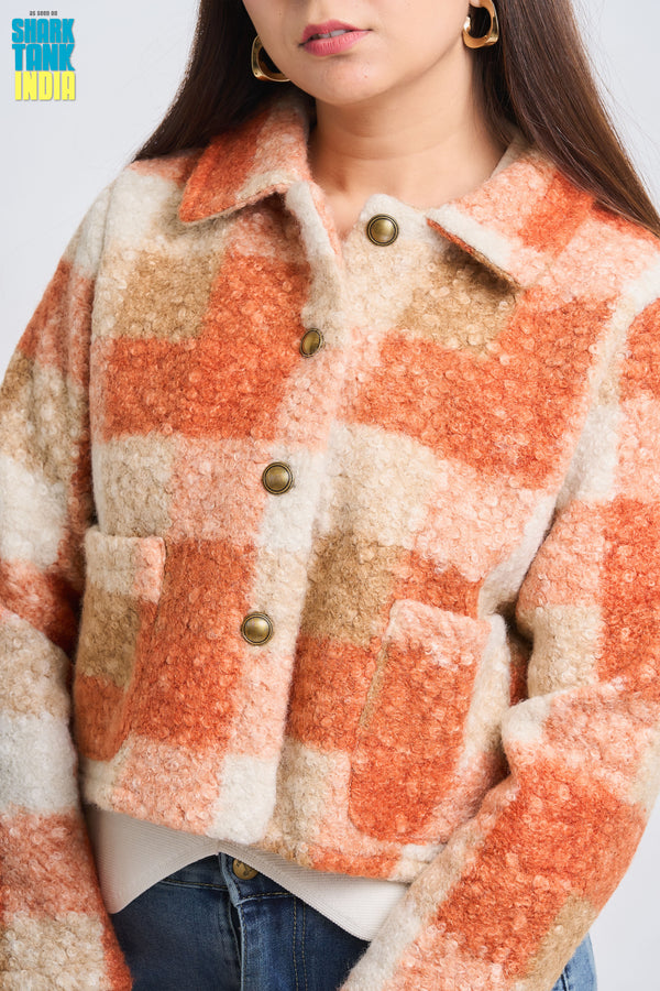 Person wearing a checkered jacket with orange and beige pattern on a plain background