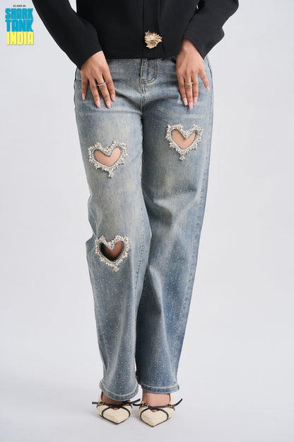 Blue jeans with heart-shaped patches worn by a person on a light gray background