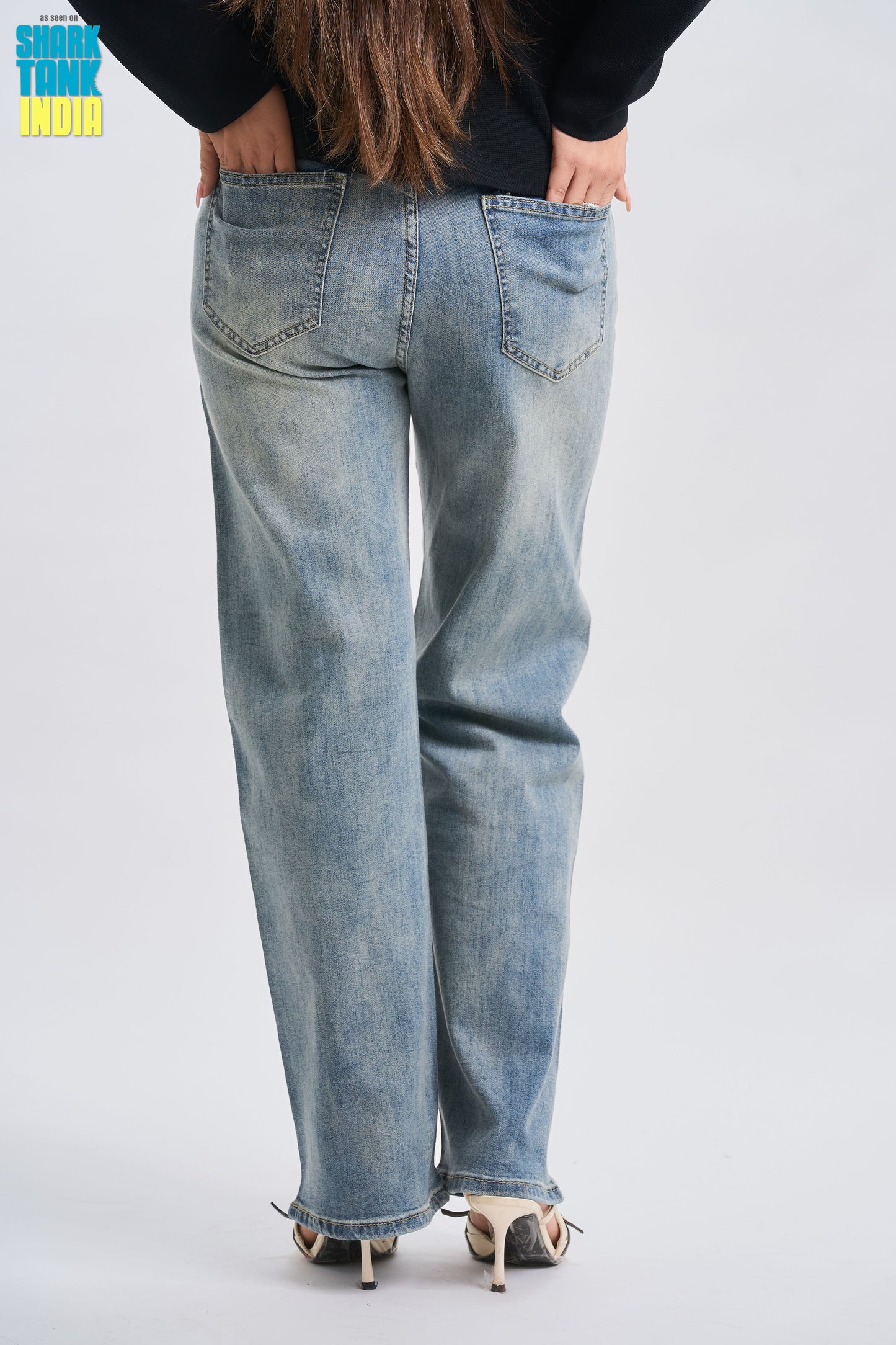 Person wearing light blue jeans on a plain background