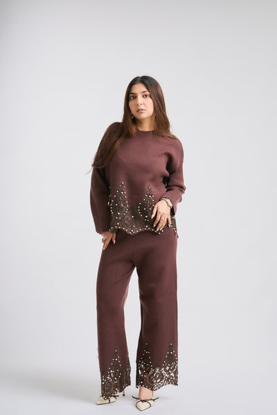 Woman wearing a brown outfit with embellishments on a white background