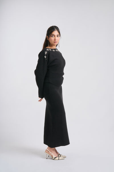 Woman wearing a black outfit with floral embellishments on a white background