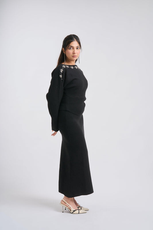Woman wearing a black outfit with floral embellishments on a white background