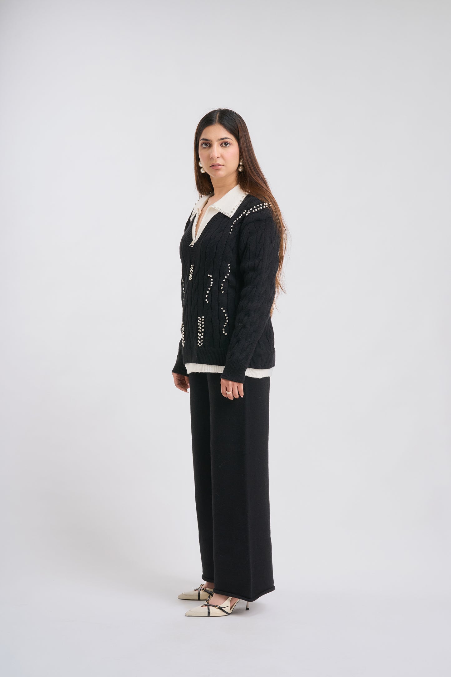Woman wearing a black cardigan with white trim on a white background