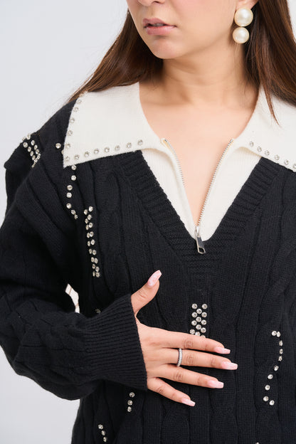 Person wearing a black cardigan with pearl embellishments on a light gray background