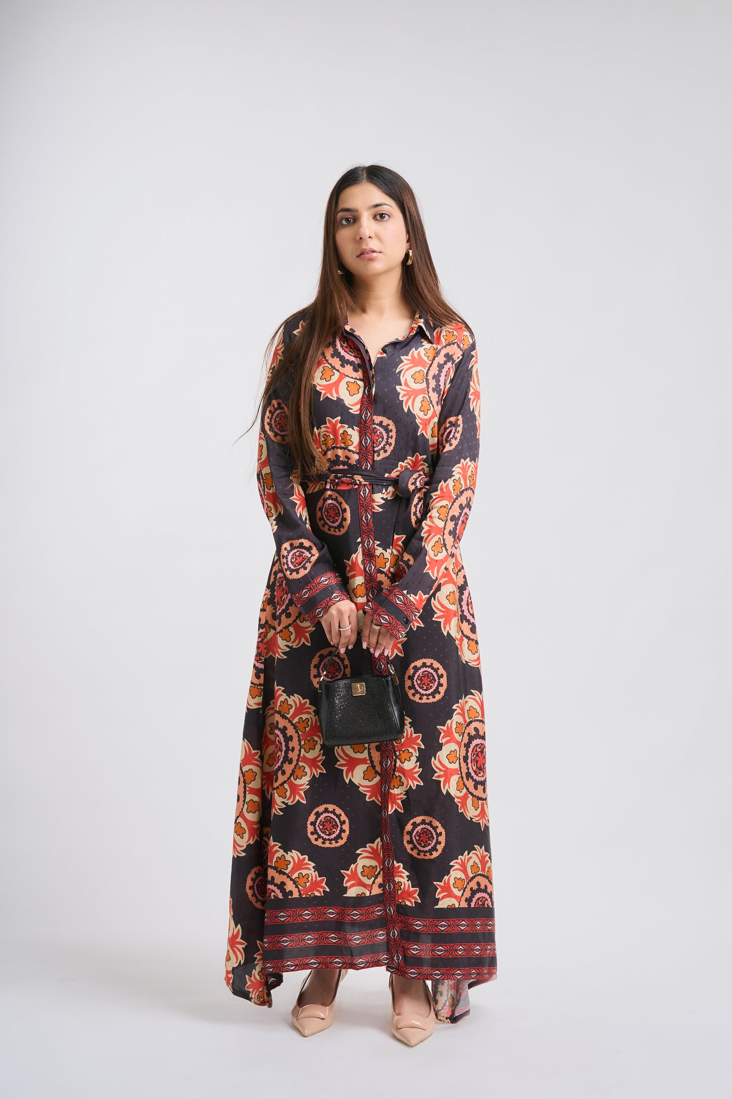 Woman wearing a long, patterned dress on a white background