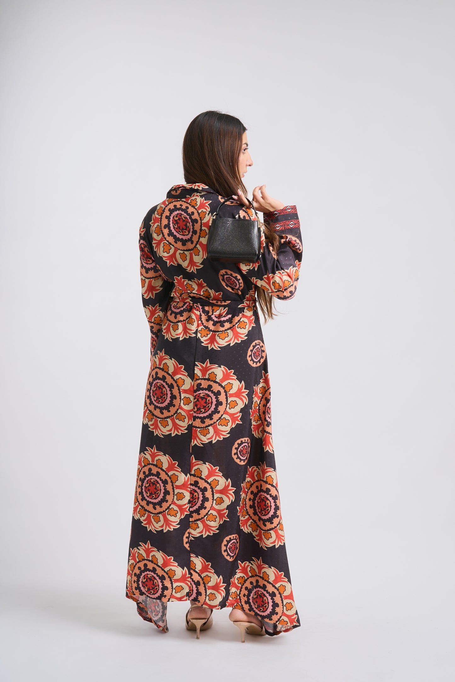 Woman wearing a long, patterned dress with a mandala design on a white background