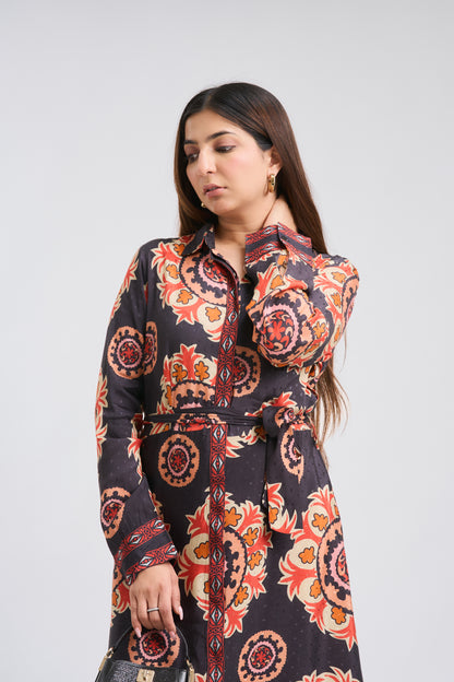 Woman wearing a long, patterned dress with a belt on a white background