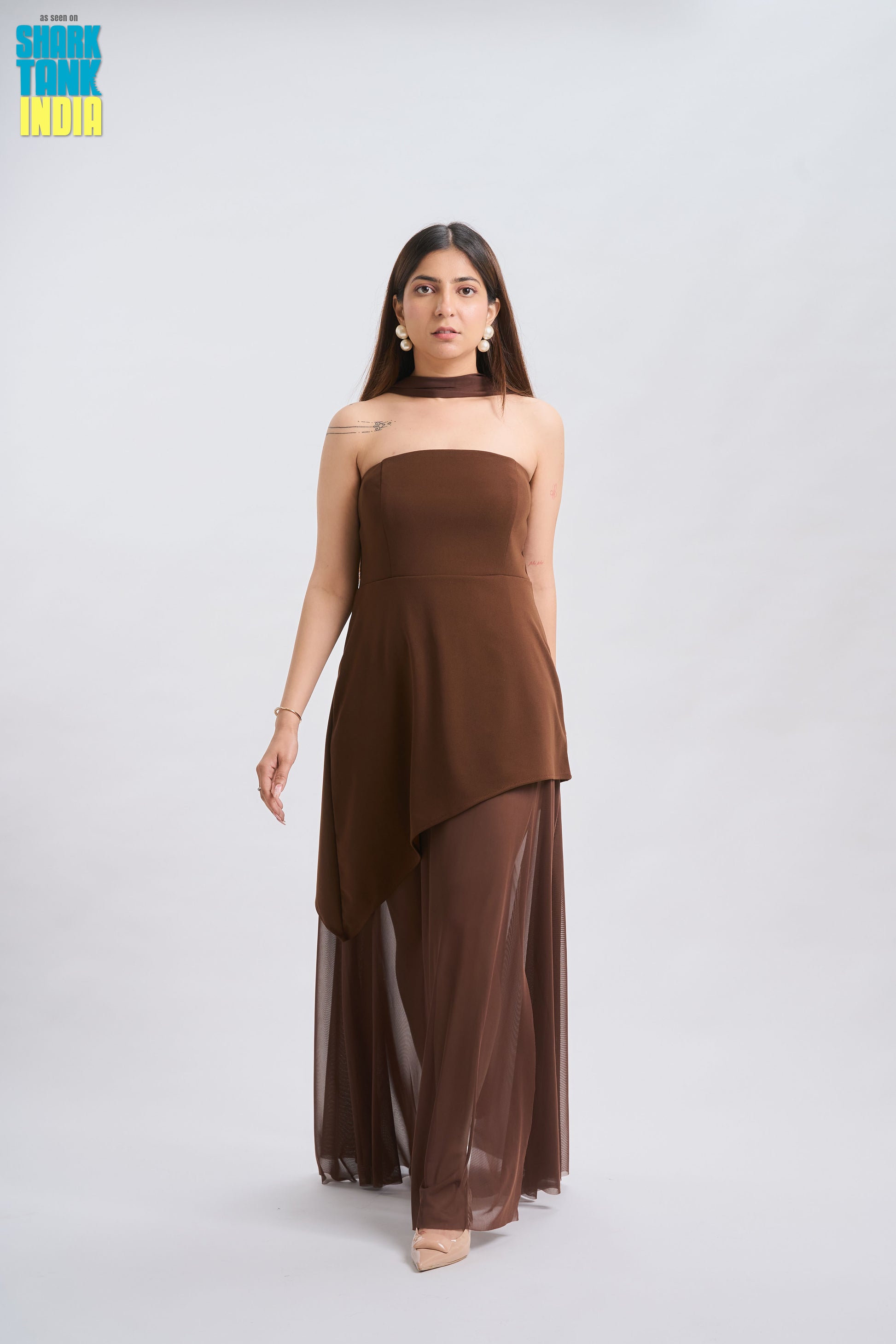 Woman wearing a brown strapless dress with sheer overlay on a white background