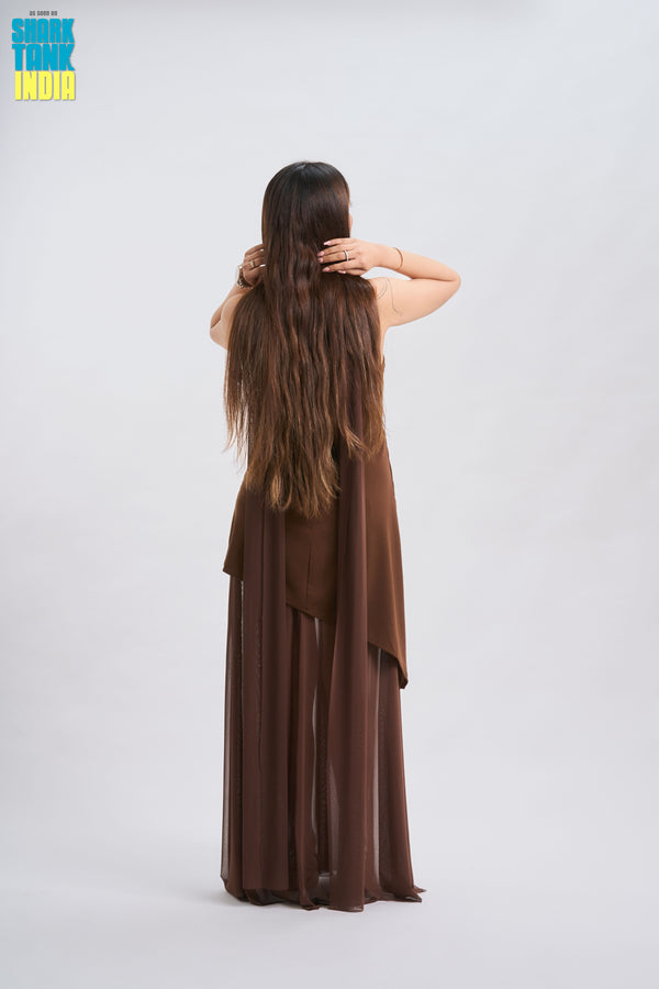 Woman in a brown dress with long hair, standing against a white background