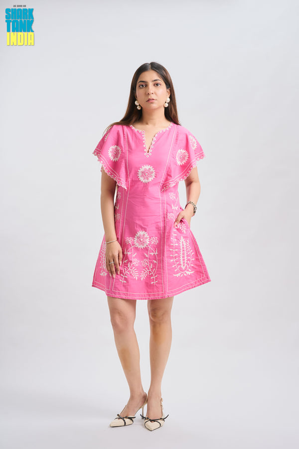 Woman wearing a pink dress with white floral patterns on a white background