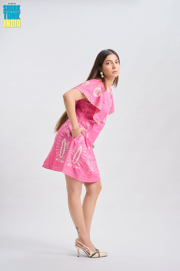 Woman wearing a pink dress with white patterns on a white background