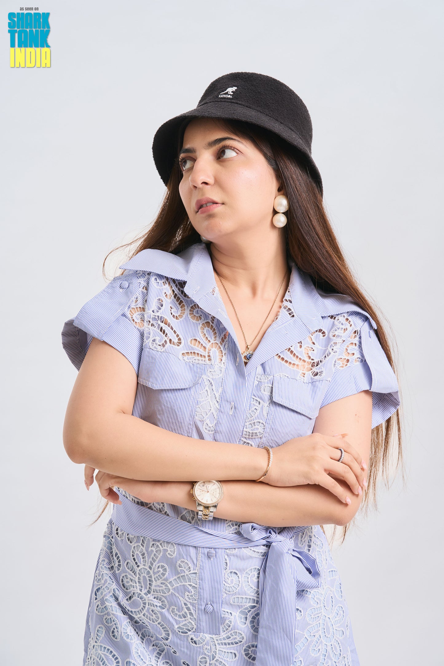 Woman wearing a black hat and light blue embroidered shirt with a white background