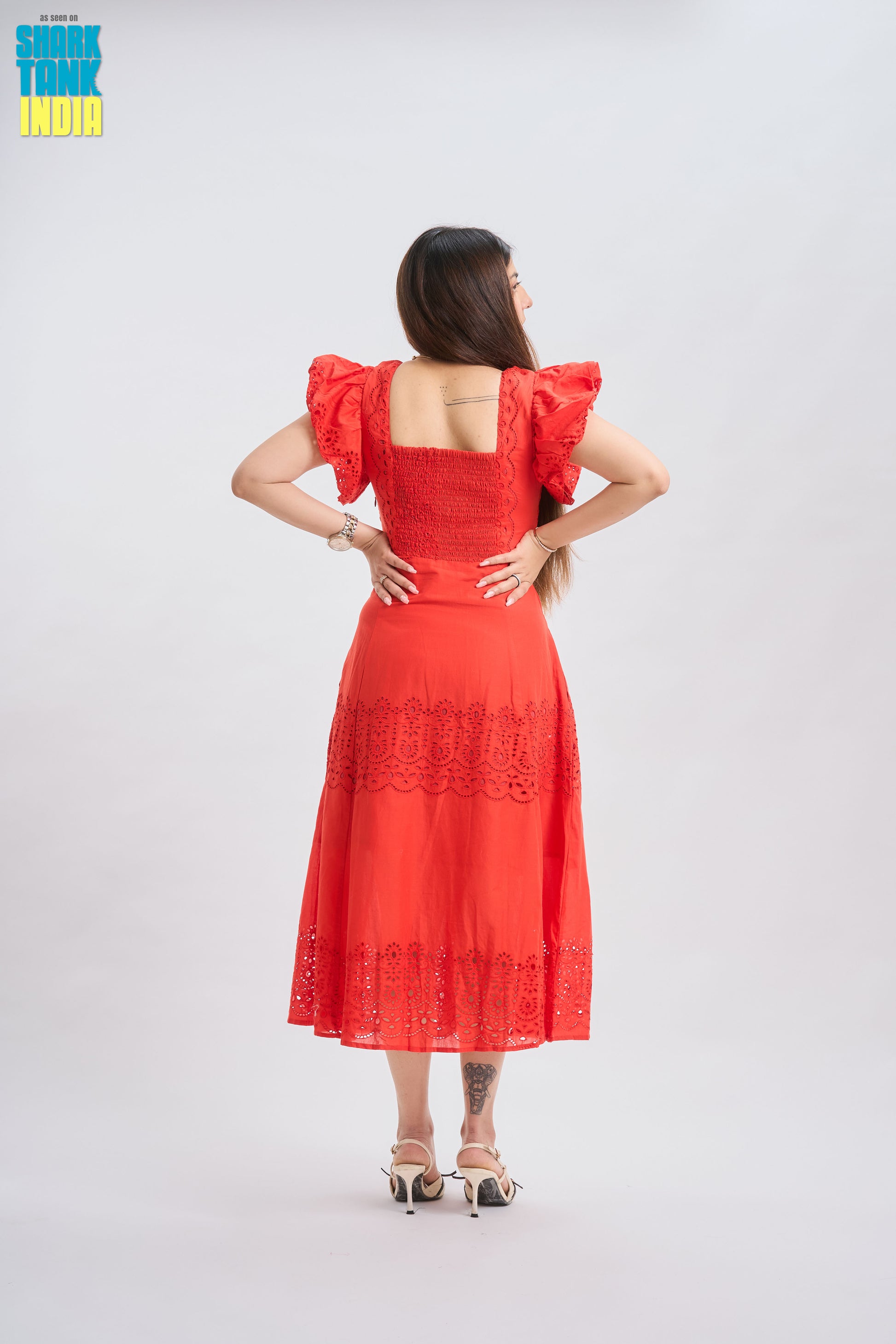 Woman wearing a red dress with ruffled sleeves on a white background