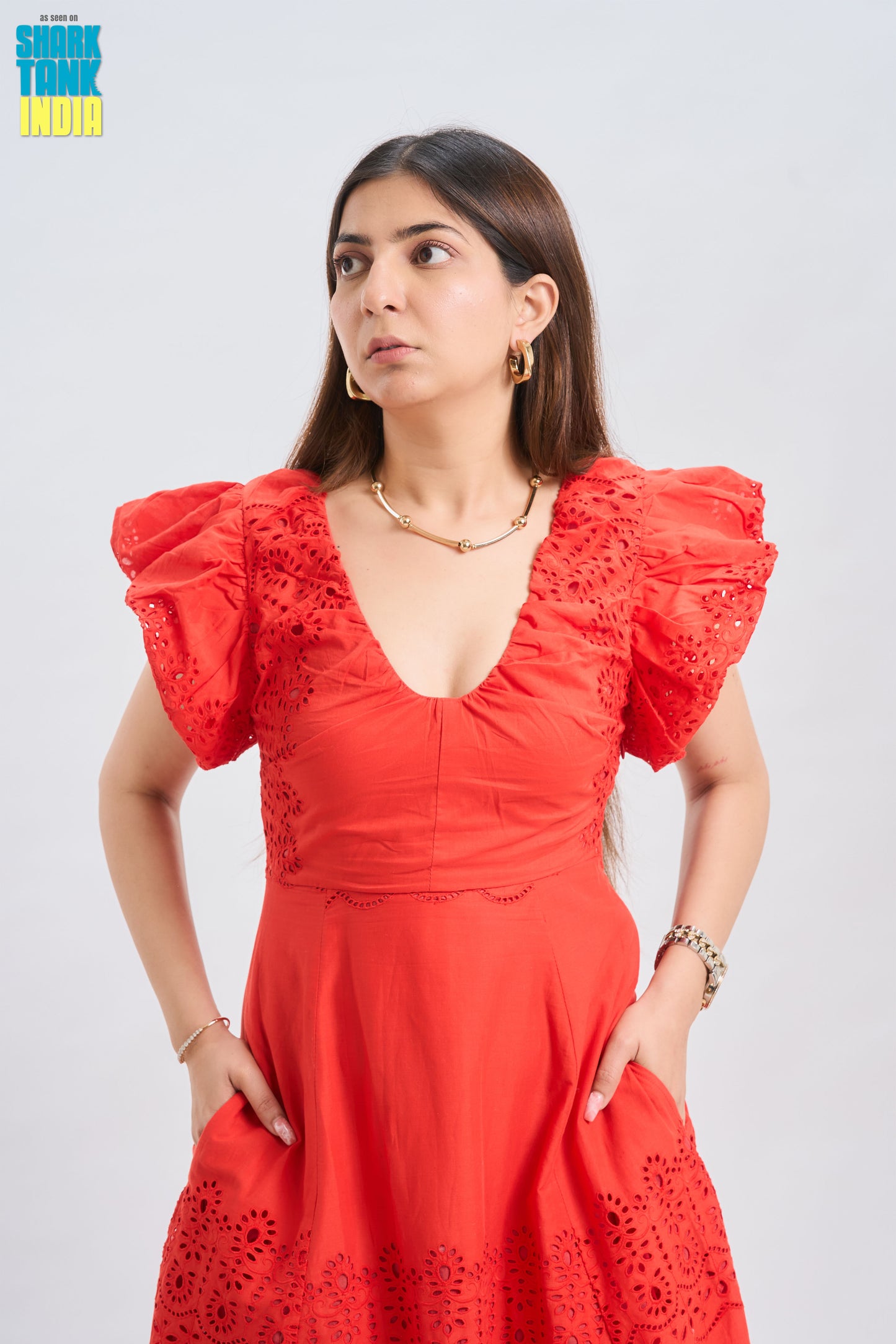 Woman wearing a red dress with ruffled sleeves against a white background