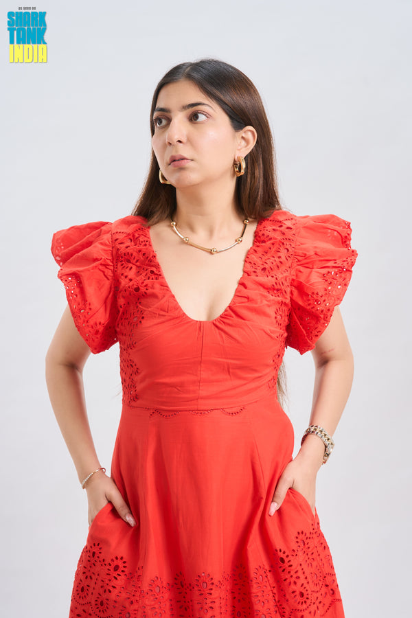 Woman wearing a red dress with ruffled sleeves against a white background