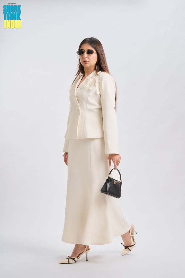 Woman wearing a white suit with sunglasses and a black handbag on a white background
