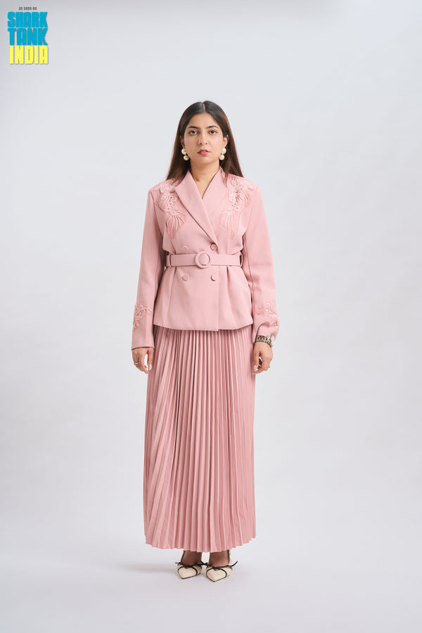 Woman wearing a pink blazer and pleated skirt on a white background