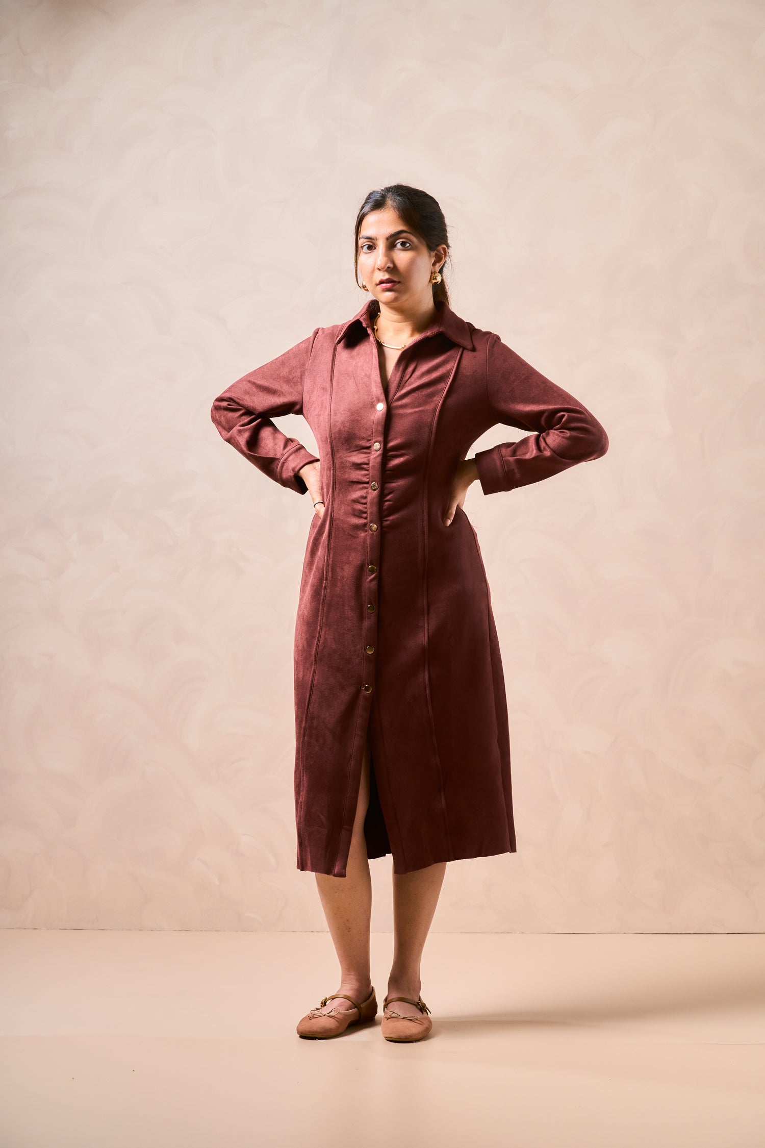 Woman wearing a burgundy dress against a beige background