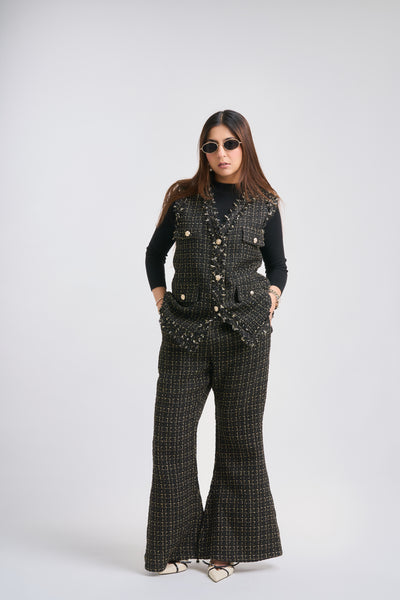 Person wearing a black patterned outfit with flared pants on a white background