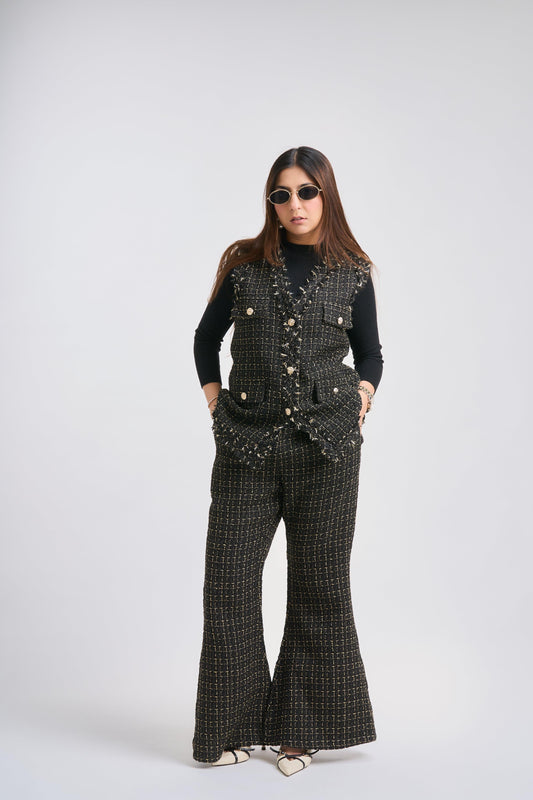 Person wearing a black patterned outfit with flared pants on a white background