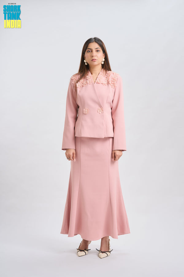 Woman wearing a pink suit with floral details on a white background