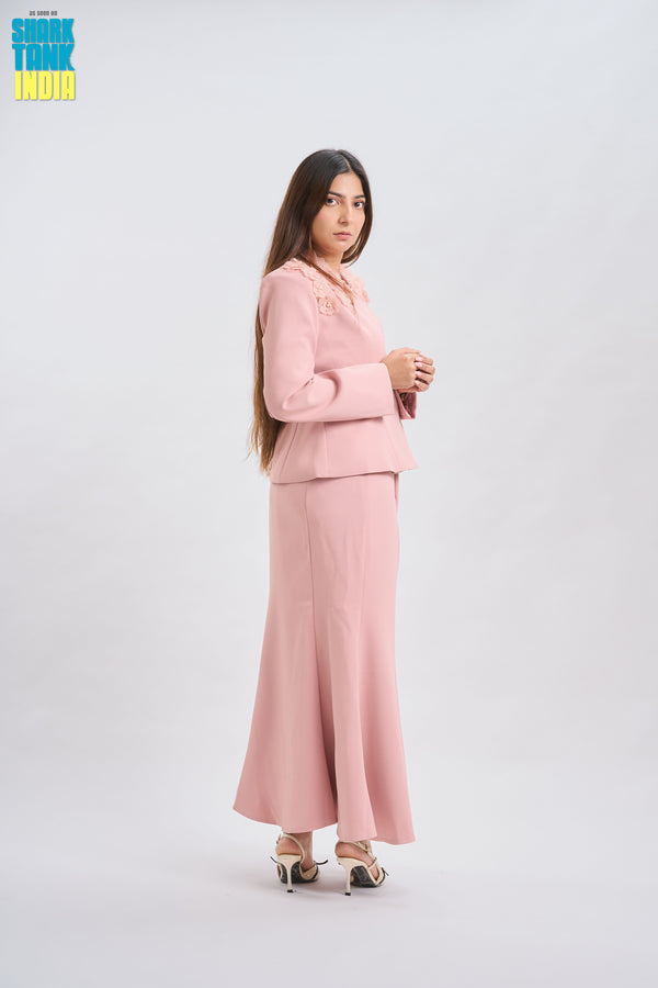 Woman wearing a pink suit standing against a white background