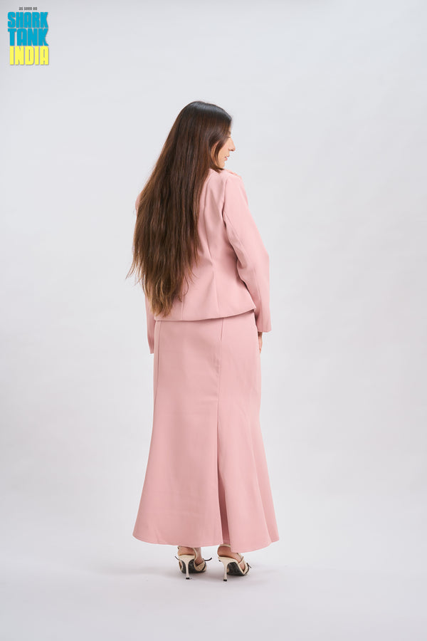 Woman wearing a pink suit standing against a white background