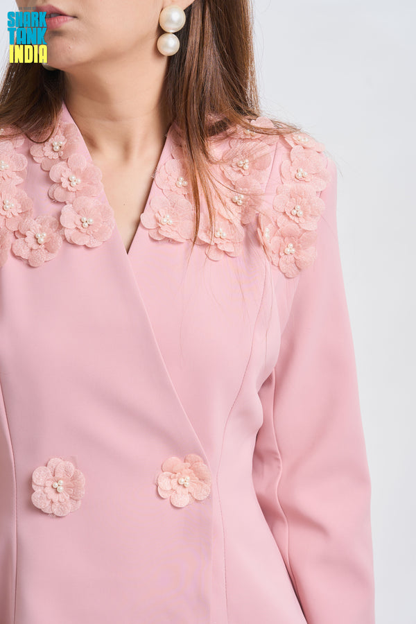 Close-up of a pink blazer with floral embellishments on a plain background
