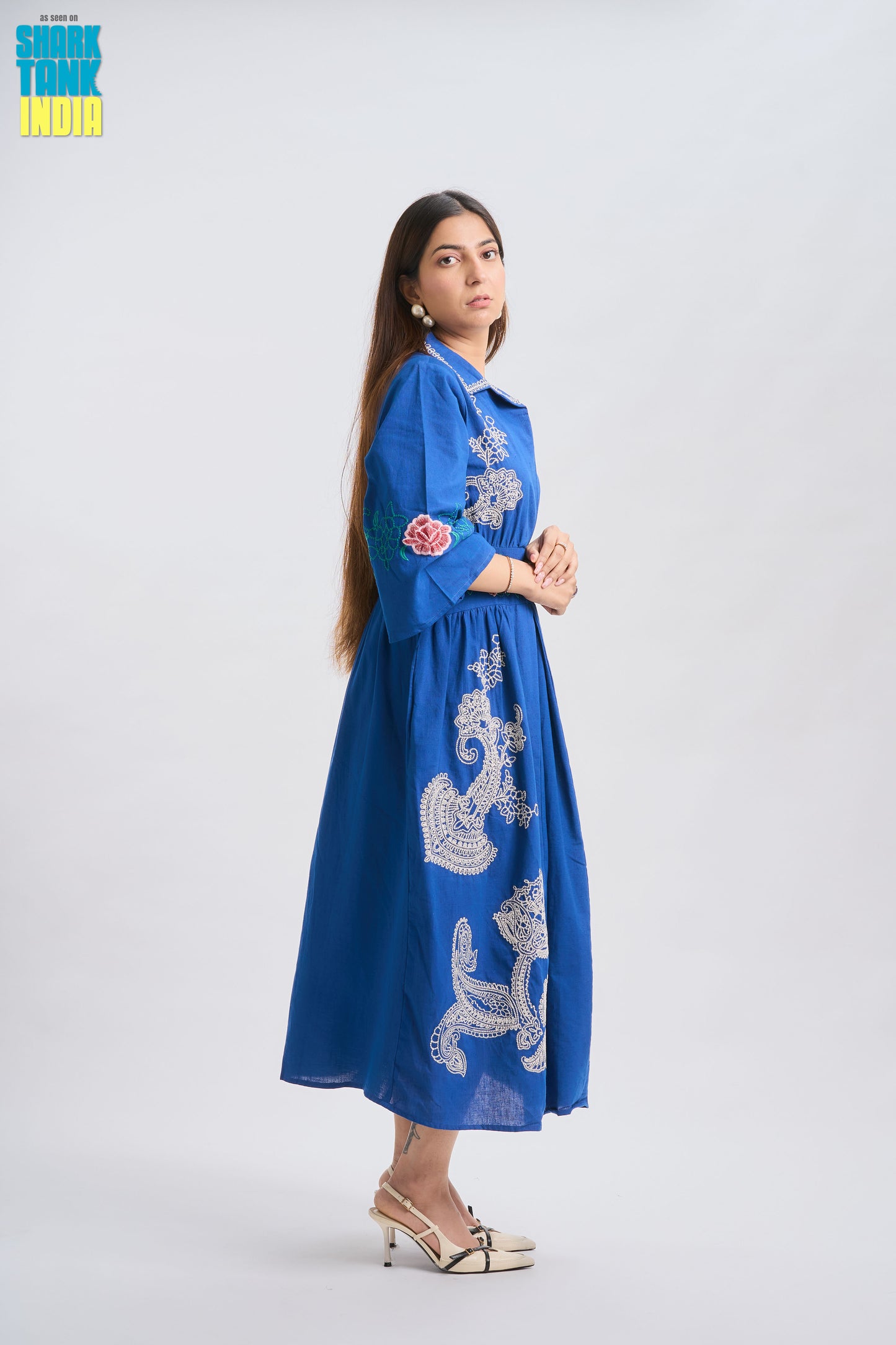 Woman wearing a blue embroidered dress on a white background