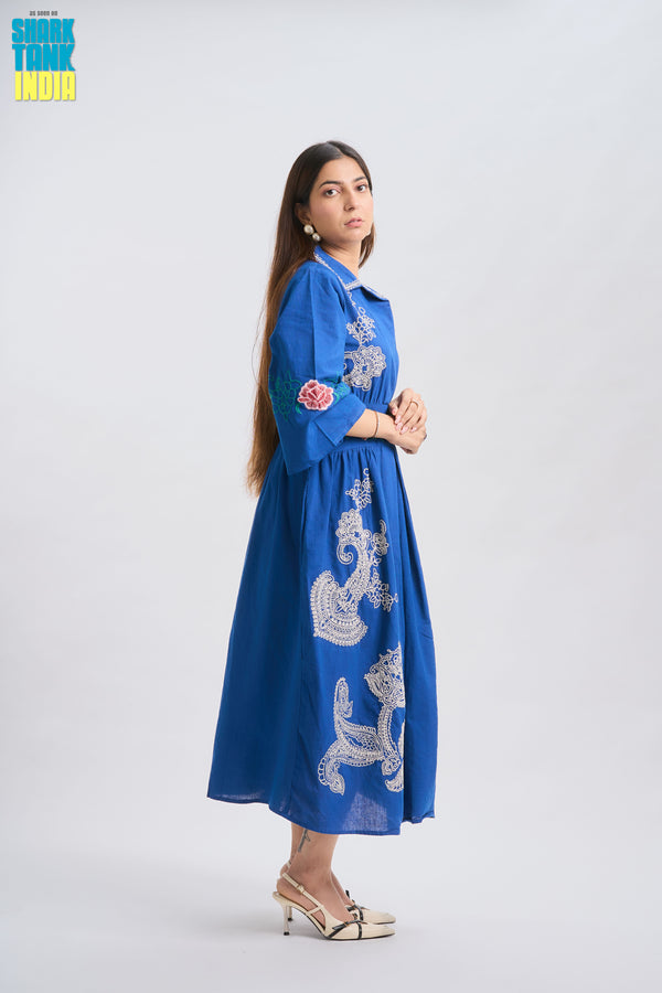 Woman wearing a blue embroidered dress on a white background
