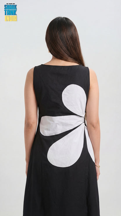 Woman wearing a black dress with a white floral design on the back against a white background