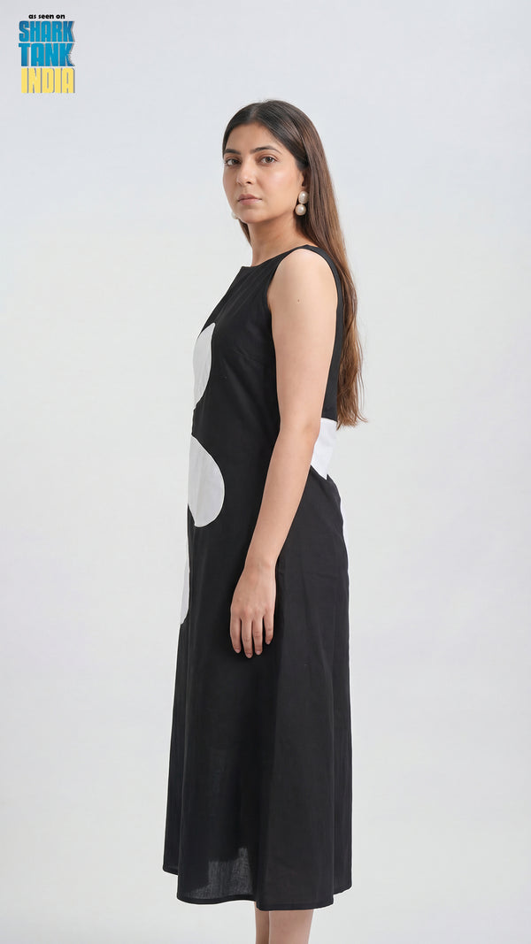 Woman wearing a black sleeveless dress with white patterns on a white background
