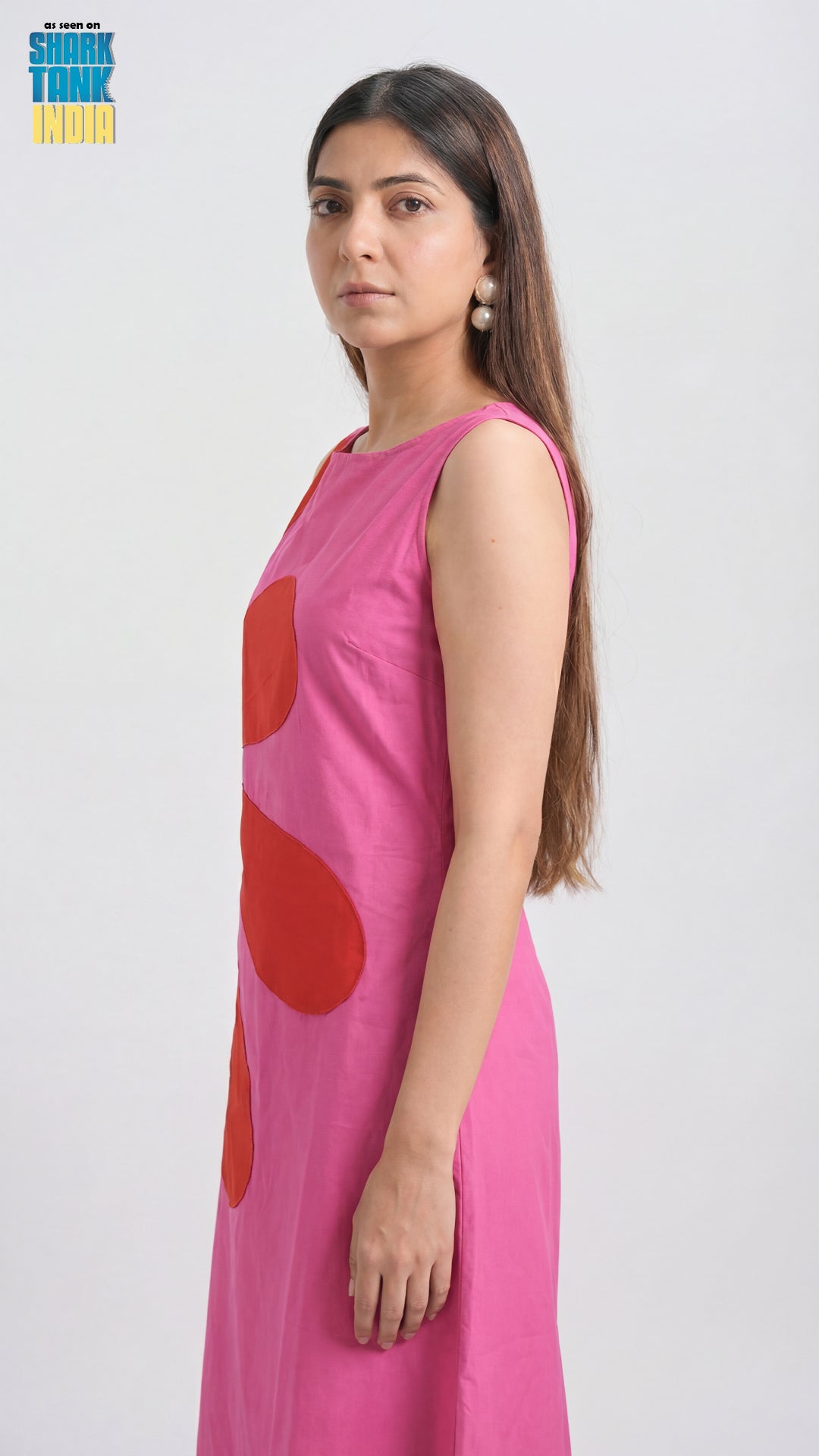 Woman wearing a pink dress with red polka dots on a white background