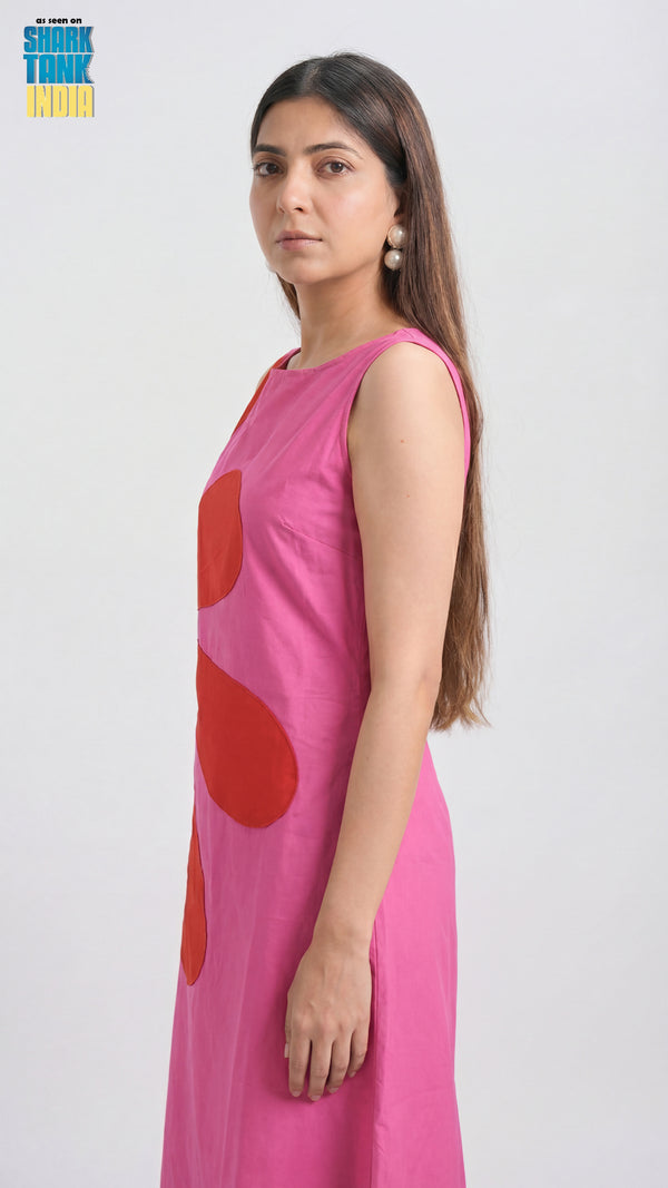 Woman wearing a pink dress with red polka dots on a white background