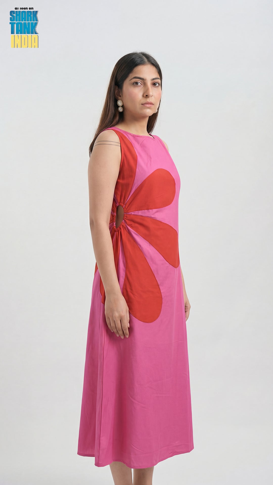 Woman wearing a pink dress with a red abstract design on a white background