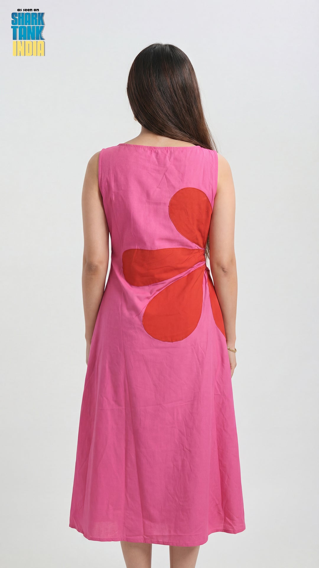 Pink dress with a red heart design on the back, worn by a person against a white background.